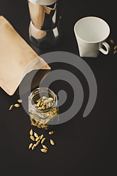 Moka pot on black background with cardamon seeds