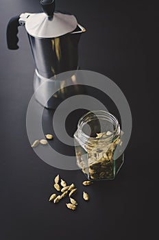 Moka pot on black background with cardamon seeds