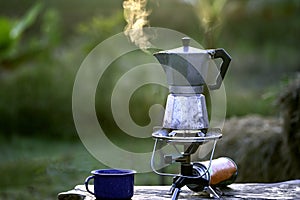 Moka pot and smoke, coffee bask on fire, In the forest at sunrise in the morning. soft focus. shallow focus effect