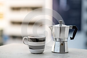 Mokapot and coffee cup and blur city background