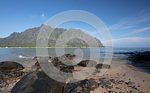 Mokolii Island [also known as Chinamans Hat] rocky beach looking toward Kualoa mountains on the North Shore of Oahu Hawaii United