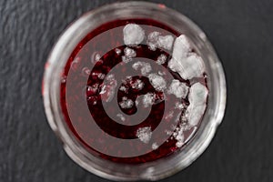 Mold in a glass jar of red raspberry jam, close up, top view. Mold is very dangerous to health