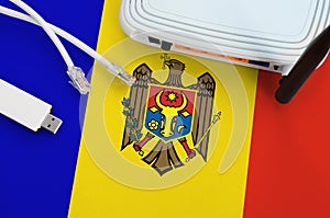 Moldova flag depicted on table with internet rj45 cable, wireless usb wifi adapter and router. Internet connection concept