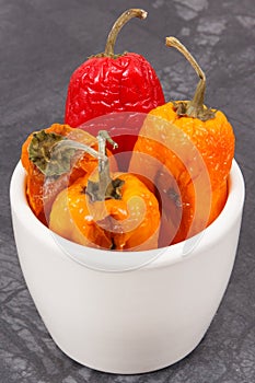 Moldy and wrinkled peppers in white bowl. Unhealthy, decompose, spoiled vegetable