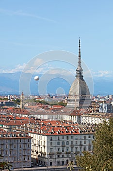 Mole Antonelliana tower and hot air balloon over Turin rooftops in a sunny day in Italy