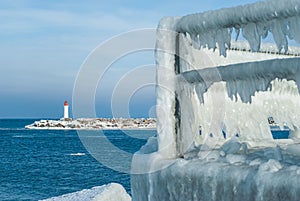 Mole with lighthouse, frozen fence and concrete tetrapods on a winter day, Ventspils, Latvia