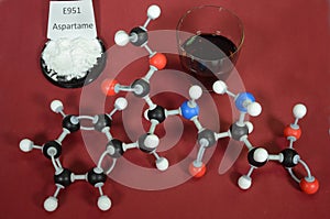 Molecule model of Aspartame a controversial artificial sweetener with associated samples. White is Hydrogen, black is Carbon, red