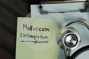 Molluscum Contagiosum write on a paperwork isolated on Wooden Table photo