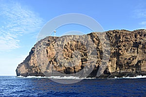 Molokini Crater rock from the Pacific Ocean, mountain in the background, Hawaiian Island of Maui