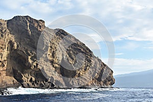Molokini Crater rock from the Pacific Ocean, mountain in the background, Hawaiian Island of Maui