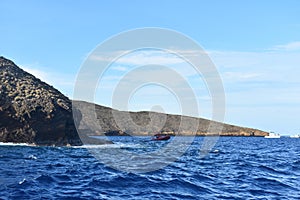 Molokini Crater rock in the Pacific Ocean near the Hawaiian Island of Maui under a blue sky