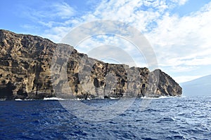 Molokini Crater rock in the Pacific Ocean near the Hawaiian Island of Maui under a cloudy sky