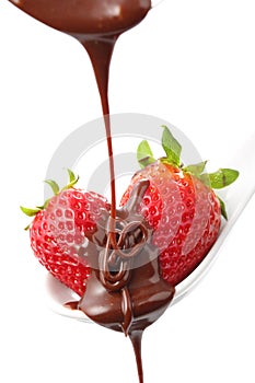 Molten chocolate being poured over two strawberries