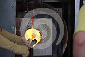 Molten glass on a metal rod in a furnace for glass blowing macro