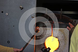 Molten glass on a metal rod in a furnace for glass blowing macro