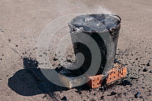 Molten hot tar in a bucket on the bricks. Roof repair