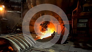 Molten iron flowing in a steel mill with many sparcles flying into the sides. Stock footage. Hot shop of the steelmaking