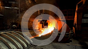 Molten iron flowing in a steel mill with many sparcles flying into the sides. Stock footage. Hot shop of the steelmaking