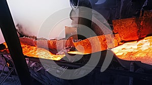 Molten material flows and cools in factory. Stock footage. Molten substance flows like lava down drain and is cooled by