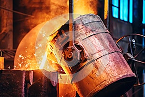 Molten metal pour from ladle Into sand mold. Iron casting process in metallurgy foundry plant, heavy industry