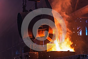 Molten metal is poured with sparks from ladle into mold. Smelting of multi-ton cast iron parts in foundry. Metallurgical