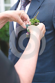 Mom adds boutonniere for the groom`s suit