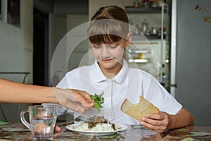 Mom adds fresh herbs to her daughter`s plate, daughter dines