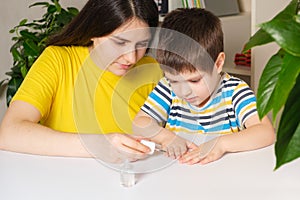 Mom applies bitter nail polish to the boy's nails to wead him from the bad habit of biting his nails