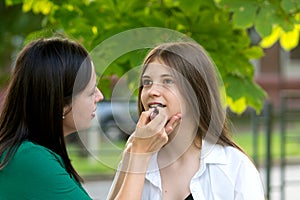 Mom applying lipstick to teenage daughter\'s lips