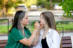 Mom applying lipstick to teenage daughter\'s lips