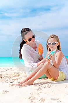 Mom applying sun cream to kid nose on the beach. The concept of protection from ultraviolet radiation