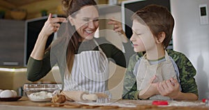 Mom and baby boy cut out homemade cookies with shapes form. Plays and draws on the face with flour Slow motion