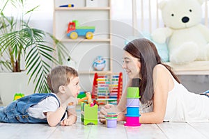 Mom and baby boy play at home with educational toys in the children`s room. A happy, loving family