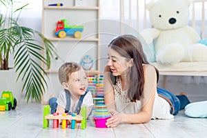 Mom and baby boy play at home with educational toys in the children`s room. A happy, loving family