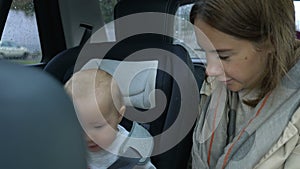 Mom and baby girl ride in the car in the back seat