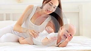 mom and baby playing having fun together in the children's bright room on the bed, happy motherhood with maternity