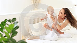 mom and baby playing peek-a-boo having fun together in the children's bright room on the bed, happy motherhood with