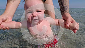 Mom with a baby in the sea water. Child body tempering. Train kids.