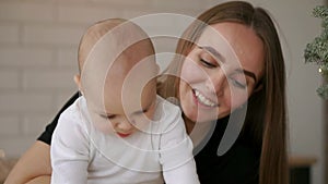 Mom and and baby sitting at the table playing tablet computer pressing your fingers on the screen and laughing