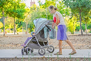 Mom with baby stroller walks in the park