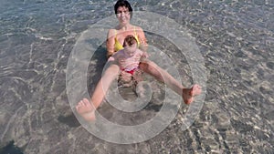 Mom with a baby in the water while relaxing at sea. Child body tempering.