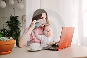 Mom and baby. a young mother working with laptop in and talk on the phone