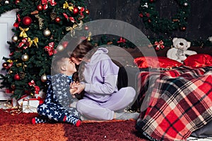Mom and boy open presents at Christmas tree decor new year