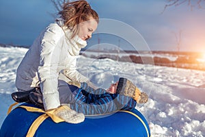 Mom with a boy son 3 years old, in the winter in a pair on a hill, fresh air. Holiday weekend city park. They play on an