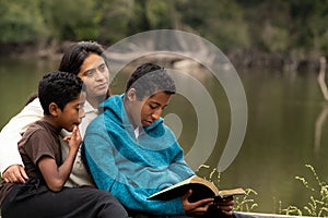 Mom and Boys Studying the Bible by River Front