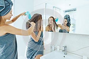 Mom brushing hair to her daughter in hotel bathroom