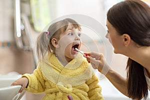 Mom brushing kid`s teeth
