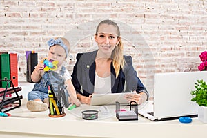 Mom and businesswoman working with laptop computer at home and playing with her baby girl.