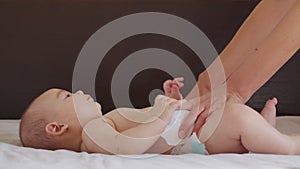 Mom changes diaper baby at night. Beautiful caucasian girl mother changes diaper to her little child. Close-up.