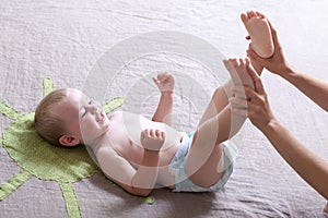 Mom changing diaper to the baby lying on his back